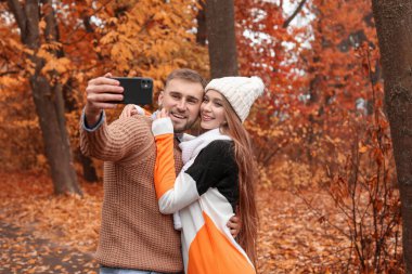Sonbahar parkında selfie çeken sevimli genç bir çift.