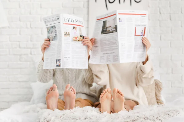 Hermosa pareja joven leyendo periódicos en la cama en casa — Foto de Stock