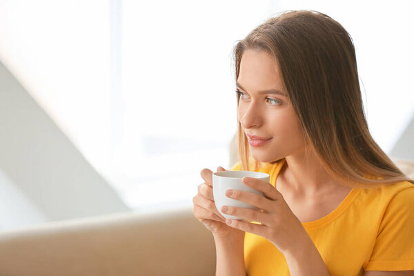 Young woman with cup of coffee resting at home