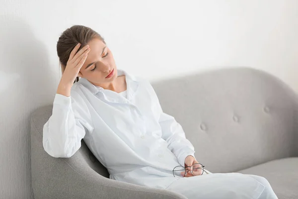 Depressed female doctor sitting on couch in clinic — Stock Photo, Image