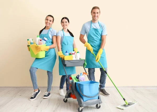 Janitors with cleaning supplies near light wall — Stock Photo, Image