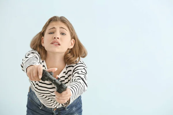 Emotional teenager girl with game pad on light background — Stock Photo, Image