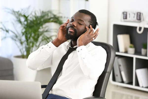 Jóképű afro-amerikai férfi zenét hallgat az irodában — Stock Fotó