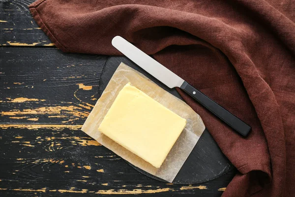 Lekkere verse boter en mes op donkere houten ondergrond — Stockfoto