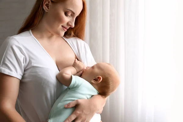 Jovem mulher amamentando seu bebê em casa — Fotografia de Stock