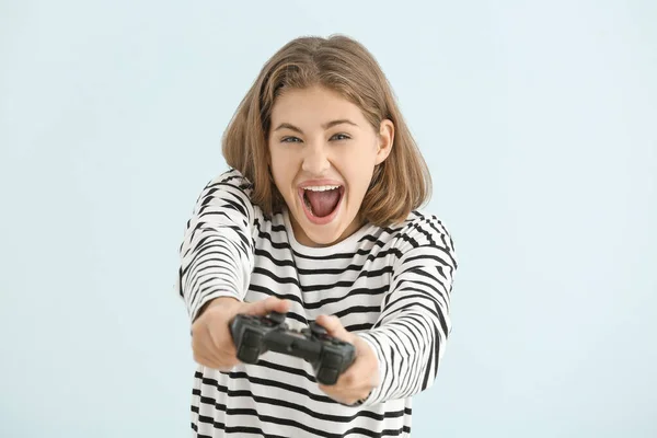 Emotionele tiener meisje met spel pad op lichte achtergrond — Stockfoto