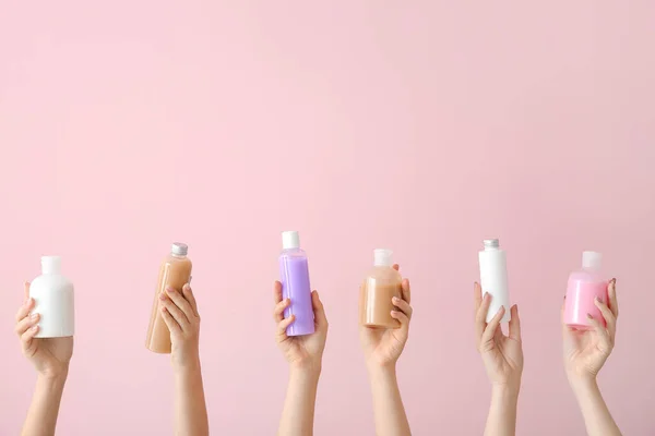 Frauenhände mit verschiedenen Kosmetikprodukten in Flaschen auf farbigem Hintergrund — Stockfoto