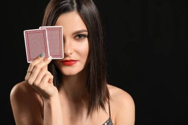 Koyu arkaplanda oyun kartları olan güzel bir genç kadın.