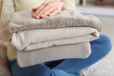 Evde bir yığın temiz giysisi olan bir kadın, yakın plan.