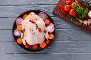 Tahta arka planda çiğ tavuk ve sebzeli kızartma tavası.