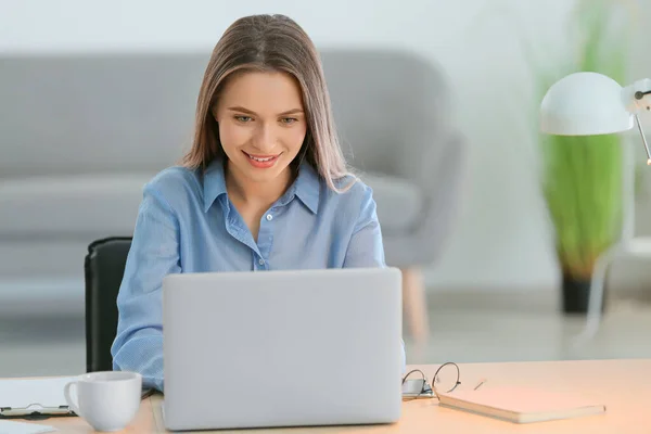 Beautiful young woman working on laptop at table — Stock Photo, Image