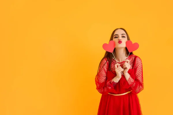 Beautiful young woman with red hearts on color background. Valentine's Day celebration — ストック写真