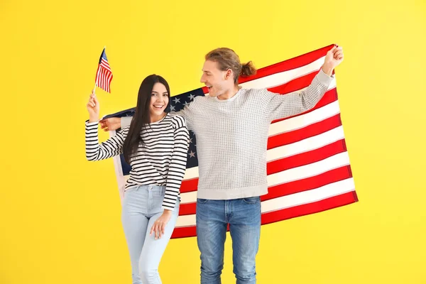 Happy young couple with national flags of USA on color background — 스톡 사진