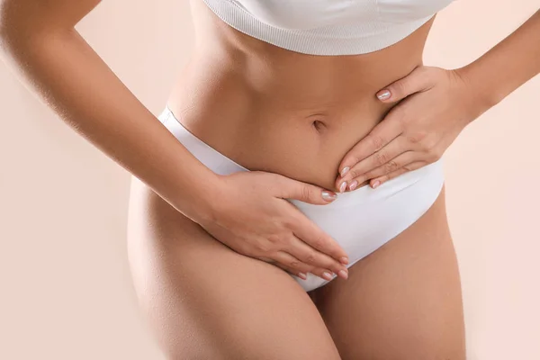 Mujer joven que sufre de dolor abdominal en el fondo claro. Concepto ginecológico — Foto de Stock