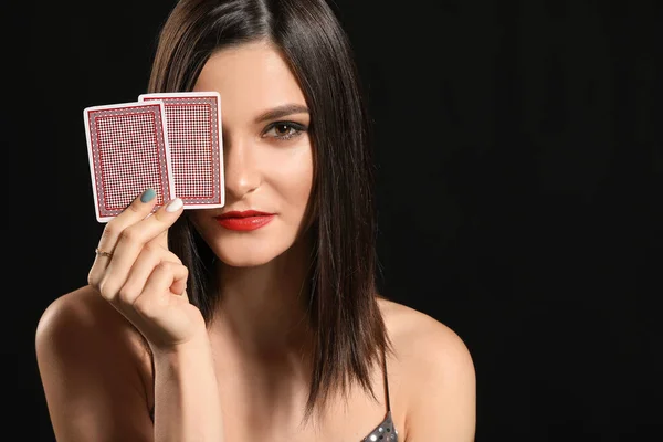 Koyu arkaplanda oyun kartları olan güzel bir genç kadın. — Stok fotoğraf