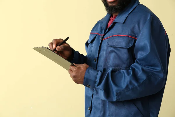 African-American car mechanic on color background — Stock Photo, Image