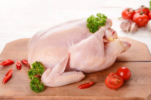 Raw chicken with chili and tomato on wooden background