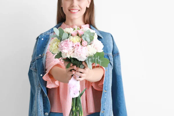 Beautiful young woman with bouquet of carnation flowers on light background — Stock Photo, Image