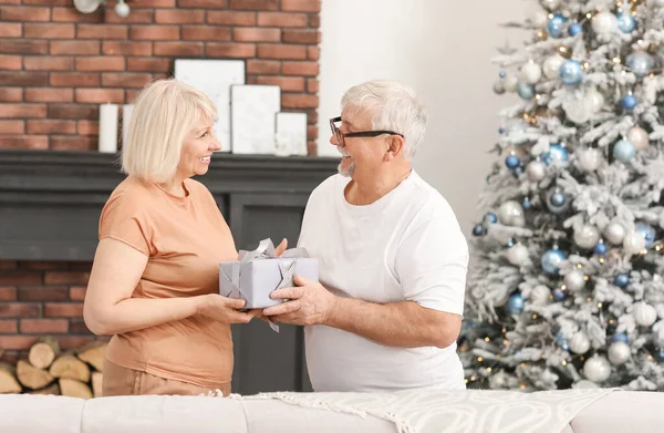 Gammal man hälsar sin fru med julklapp hemma — Stockfoto