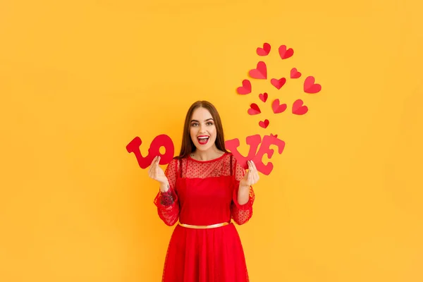 Bella giovane donna con la parola AMORE e cuori su sfondo a colori. Festa di San Valentino — Foto Stock