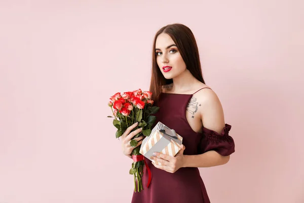 Mulher bonita com flores e presente no fundo de cor. Celebração do Dia dos Namorados — Fotografia de Stock