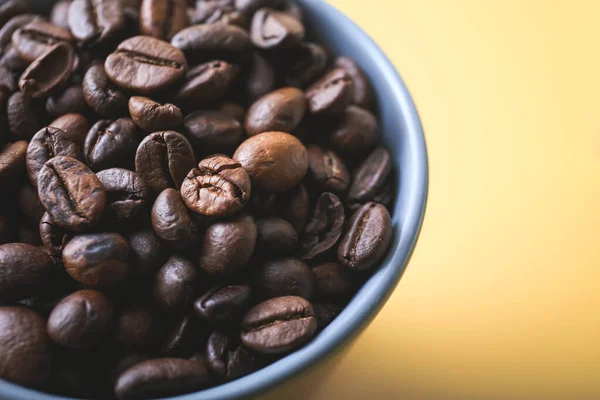 Cup with roasted coffee beans on color background, closeup — Stock Photo, Image