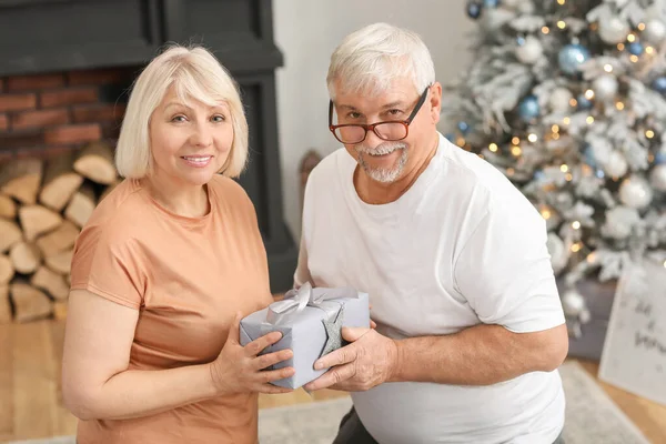 Gammal man hälsar sin fru med julklapp hemma — Stockfoto