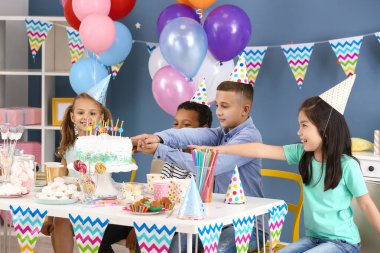 Küçük çocuklar evde doğum günü kutluyor.