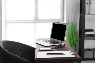 Ofisinde dizüstü bilgisayarı olan modern şık bir iş yeri.