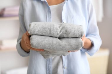 Evde bir yığın temiz giysisi olan bir kadın, yakın plan.