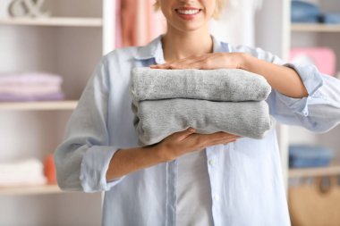 Evde bir yığın temiz giysisi olan bir kadın, yakın plan.