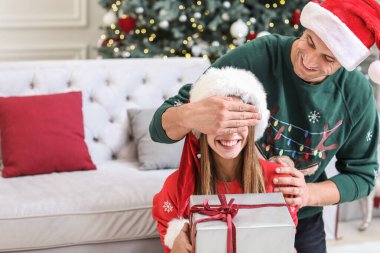 Mutlu genç adam Noel hediyesini evdeki kız arkadaşına veriyor.