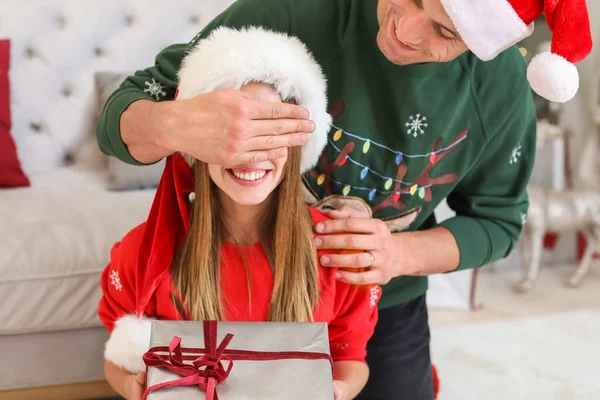 Jovem feliz dando presente de Natal para sua namorada em casa — Fotografia de Stock