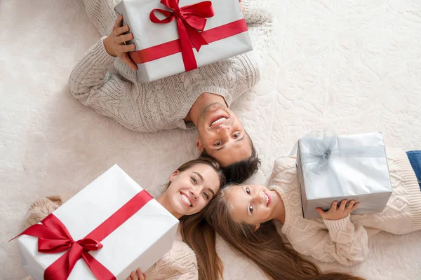 Jovem família feliz com presentes de Natal deitado no chão, vista superior — Fotografia de Stock