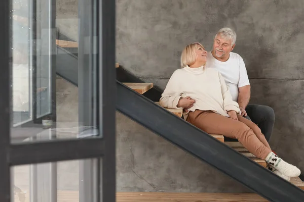 Happy mature couple sitting on steps at home — Stock Photo, Image