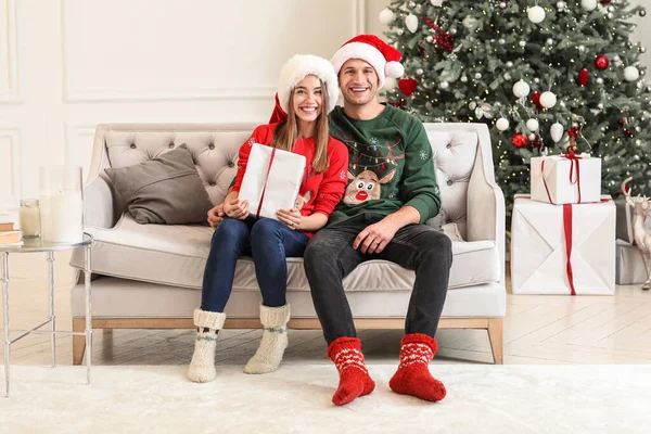 Happy young couple with Christmas gift at home — Stock Photo, Image