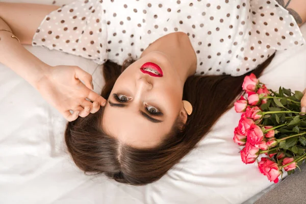 Hermosa joven con ramo de flores acostado en la cama. Celebración de San Valentín — Foto de Stock