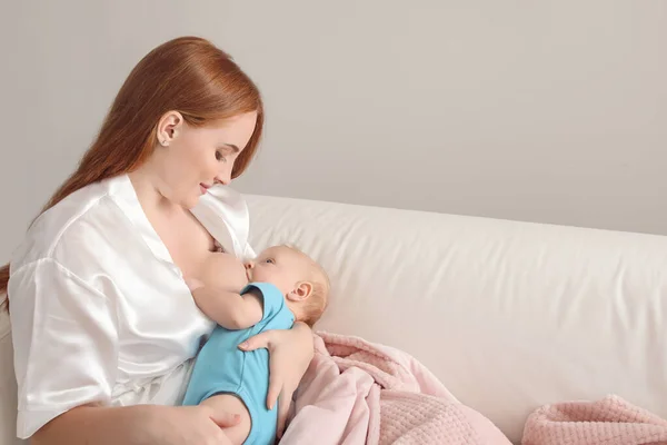 Молодая женщина кормит грудью своего ребенка дома — стоковое фото
