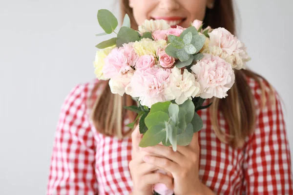 Beautiful young woman with bouquet of carnation flowers on light background, closeup — Stock Photo, Image