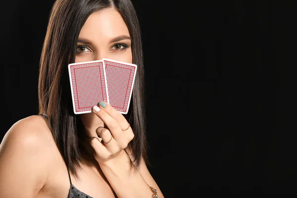 Koyu arkaplanda oyun kartları olan güzel bir genç kadın. — Stok fotoğraf