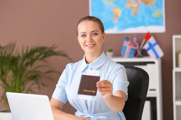 Female travel agent with passport and ticket in office