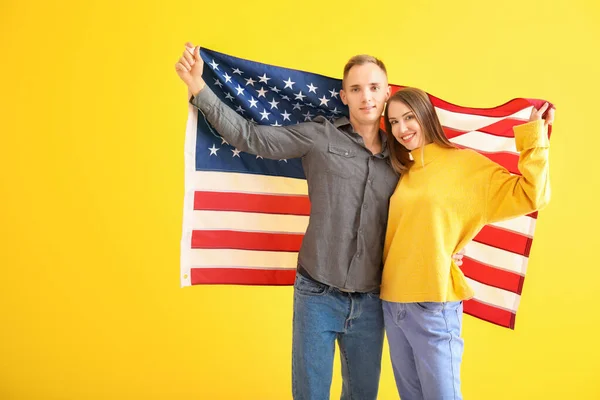 Happy young couple with national flag of USA on color background — Stock Photo, Image