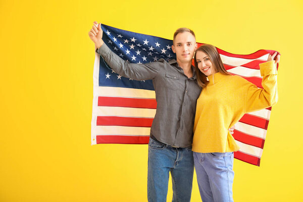 Happy young couple with national flag of USA on color background