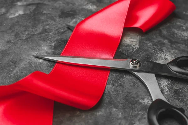 Scissors and red ribbon on grunge background — ストック写真