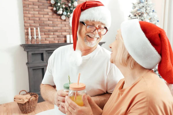 Happy mature couple drinking juice on Christmas eve at home — Stock Photo, Image