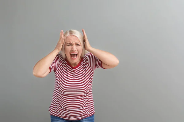 Mujer madura enojada sobre fondo gris —  Fotos de Stock