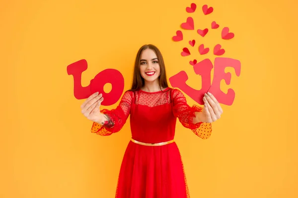 Hermosa mujer joven con palabra AMOR y corazones sobre fondo de color. Celebración de San Valentín —  Fotos de Stock