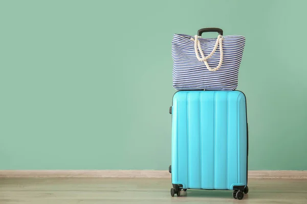 Βαλίτσα και τσάντα παραλίας κοντά σε χρωματιστό τοίχο. Ταξιδιωτική έννοια — Φωτογραφία Αρχείου