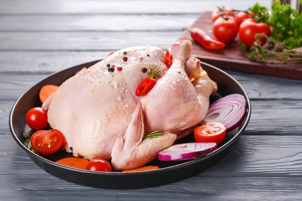 Sartén con pollo crudo y verduras sobre fondo de madera — Foto de Stock