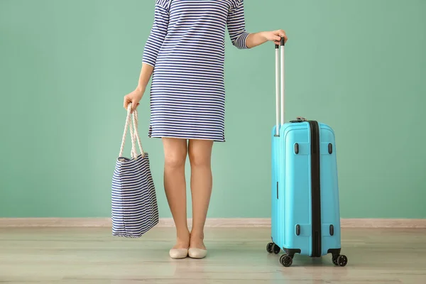 Mujer con equipaje cerca de la pared de color. Concepto de viaje — Foto de Stock